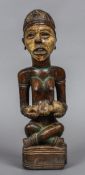 A tribal carved hardwood polychrome decorated figure Modelled seated holding a infant. 39.