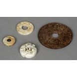 Four Chinese carved hardstone roundels The largest 10 cm diameter.