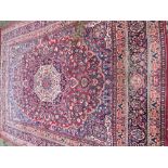 A Tabriz wool carpet The wine red field enclosing a central ivory medallion with pendant palmettes