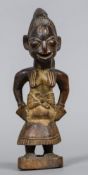 A small tribal carved wooden figure Formed as a mother carrying her child on her back. 23 cm high.