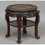 A Chinese carved hardwood table Of typical lobed form, standing on carved ball and claw feet.