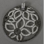 A black and white diamond set white metal pendant Of circular form, open worked with flowerheads.