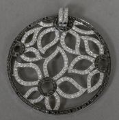 A black and white diamond set white metal pendant Of circular form, open worked with flowerheads.