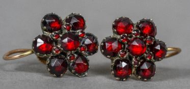 A pair of unmarked garnet set ear clips Of flowerhead form. Each 1.25 cm wide.