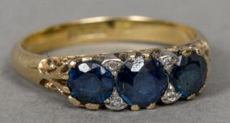 An 18 ct gold sapphire and diamond ring Set with three sapphires interspersed with diamond chips.
