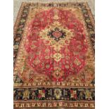 A Tabriz wool carpet The wine red field enclosing a central medallion with stylised pendant