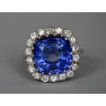 A sapphire and diamond set platinum cluster ring The large central facet cut sapphire bordered by a