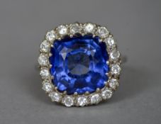 A sapphire and diamond set platinum cluster ring The large central facet cut sapphire bordered by a