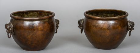 A pair of Chinese patinated bronze censors Each with twin mask headed loop handles,