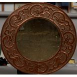An Arts & Crafts copper framed wall glass The bevelled circular plate within a broad frame worked