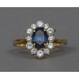 An 18 ct gold diamond and Burmese sapphire cluster ring The central sapphire bordered by a single