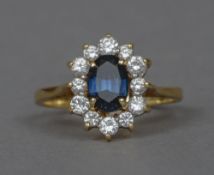 An 18 ct gold diamond and Burmese sapphire cluster ring The central sapphire bordered by a single