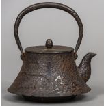 A Japanese cast iron teapot The loop handle above the removable lid and the flared main body