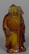 An amber coloured figure of sage Modelled holding a staff. 8.75 cm high.