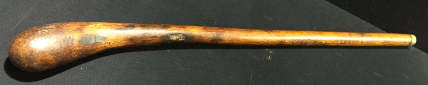 A wooden club The bulbous end opposing a brass ferrule at the other. 80 cm long.