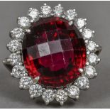 An 18 ct white gold diamond cluster ring The large facet cut central red stone flanked by a row of