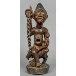 A large carved wooden tribal group Formed as a glass eyed figure holding a child and seated atop a