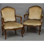 A pair of 18th century French walnut open armchairs With carved top rail and overstuffed back and
