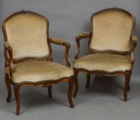 A pair of 18th century French walnut open armchairs With carved top rail and overstuffed back and