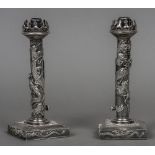 A pair of Chinese silver ejector candlesticks Each with a pierced castellated top above a dragon