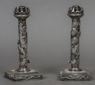 A pair of Chinese silver ejector candlesticks Each with a pierced castellated top above a dragon