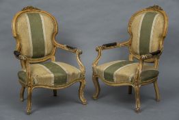 A pair of Victorian upholstered open armchairs Each florally carved top rail above the padded back