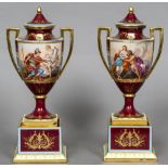 A pair of late 19th century Vienna porcelain vases on stands Each with twin gilt handles on a red