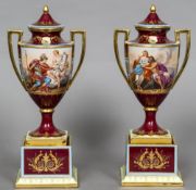 A pair of late 19th century Vienna porcelain vases on stands Each with twin gilt handles on a red