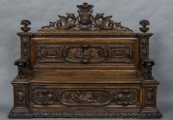 A 19th century heavily carved walnut settle The crested top above the carved back issuing mythical