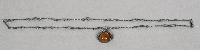 An amber pendant on chain With leaf form decorations. The chain approximately 64 cm long.