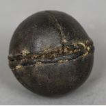 An early stitched leather ball, possibly a cricket ball 7 cm diameter.