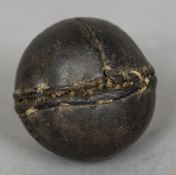 An early stitched leather ball, possibly a cricket ball 7 cm diameter.
