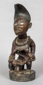 An African tribal figure Modelled as a woman with glass eyes, breast feeding a child. 43.5 cm high.