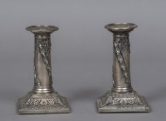 A pair of George V loaded silver candlesticks Each column worked with fruiting oak swags above a