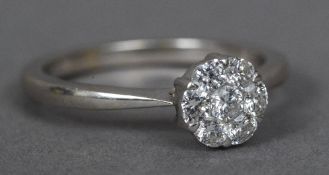 A diamond set white metal flowerhead ring The central stone approximately 1/16th of a carat.