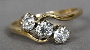 An 18 ct gold diamond set three stone crossover ring Each stone approximately 0.25 carat.