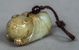 A Chinese carved pale and russet jade pendant Worked as a recumbent swaddled cat. 5.5 cm long.