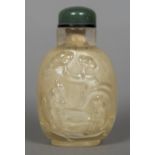 A Chinese carved rock crystal snuff bottle with jade lid Decorated with sagely figures in a garden.