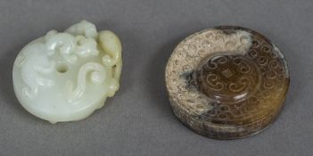 A Chinese carved pale jade roundel Worked with mythical beasts and pierced;