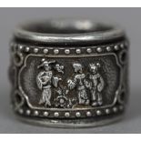 A Chinese white metal archer's ring The rotating band worked with figural vignettes. 3 cm diameter.