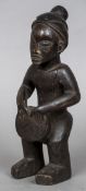 An African tribal figure Modelled holding a drum between its knees with scarification marks to