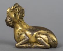 A Chinese cast bronze gilt decorated scroll weight Modelled as a recumbent goat. 7 cm wide.