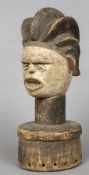 An African tribal bust Formed as a figure wearing a headdress with cowrie shell inset eyes.