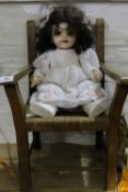 An early 20th century child's chair and a doll
