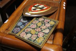 A pair of needlework pictures and a painted heraldic shield