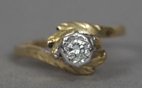 An 18 ct gold diamond solitaire ring, the illusion set stone above scrolling floral set shoulders.
