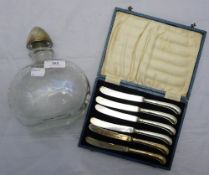 A silver topped etched glass decanter and a set of knives