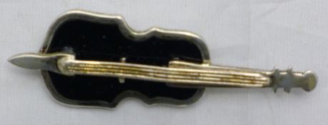 A silver brooch in the form of a violin