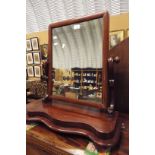 A Victorian mahogany swing mirror raised on scrolling supports and serpentine base