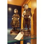 A pair of early 20thC bronze and ivory figures of a Dutch boy and girl, the boy holding a boat the